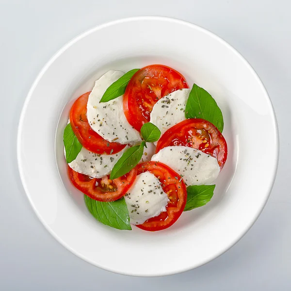 Mozzarella with tomatoes and basil On white dish — Stock Photo, Image