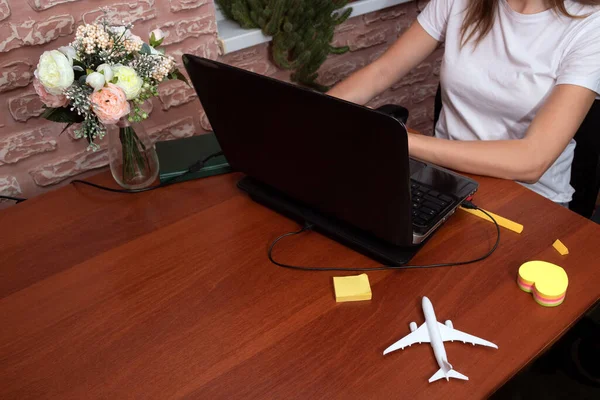 A girl is sitting at a laptop, choosing a country for the flight. Space for text. Selective focus.