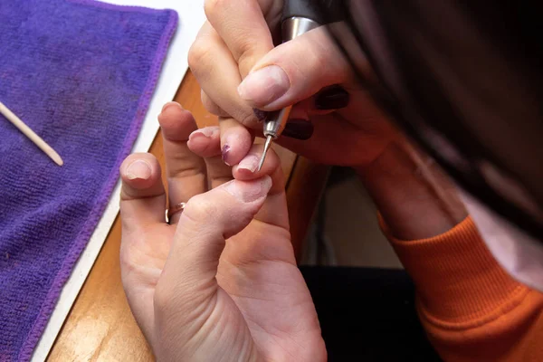 Grinding the nails with a thin cutter head. Independent home hand care. Selective focus.