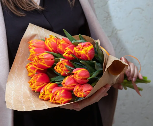 Paketteki bir buket kırmızı ve sarı lale kadınların elinde. Bahar, kadınlar için tatil zamanıdır. Seçici odak.