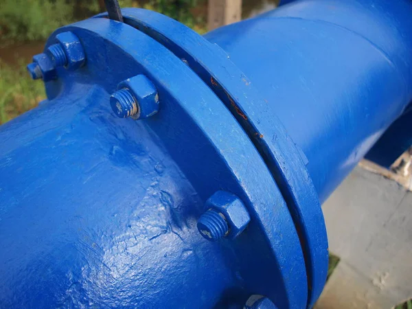 Bolts and nuts on blue plumbing. Metal joints of large outdoor pipes. Focus closely and choose the subject.