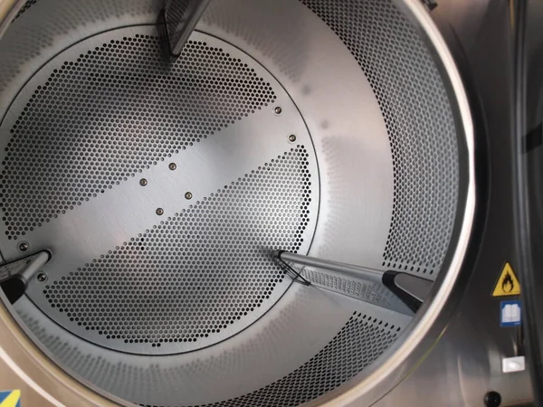タンブルドライヤーの中だ 乾燥タンクは フロントローディングタンブル乾燥機用の穿孔ステンレス鋼で作られています フォーカスを閉じて対象を選択します — ストック写真