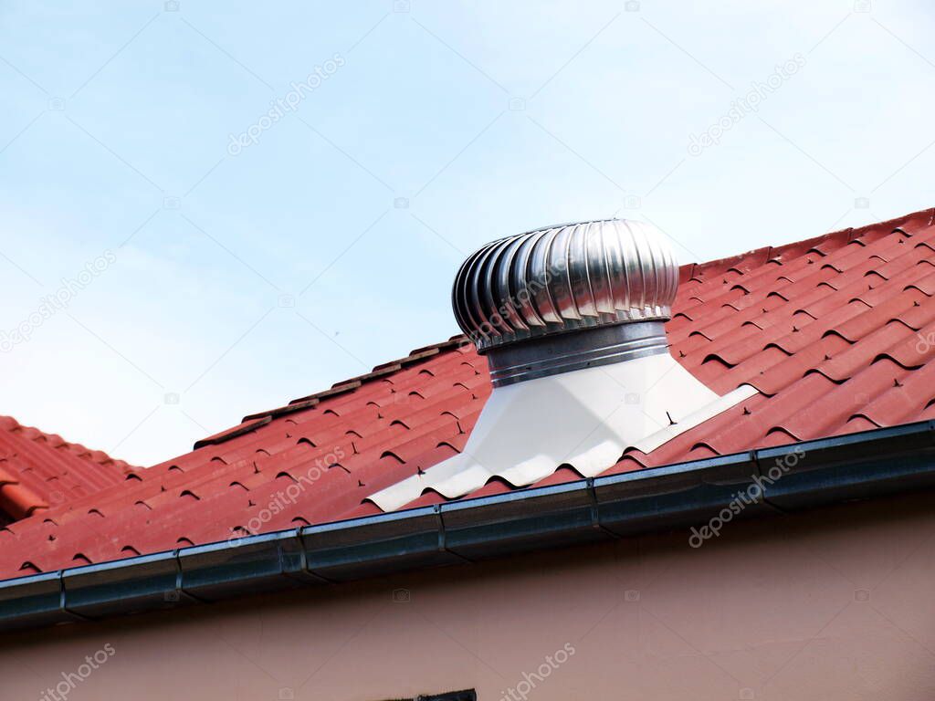 Roof ventilation on the roof. Ball spinning serves to ventilate the house or factory. On a dim blue sky background. Selective focus
