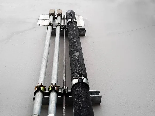 Electrical conduits and air ducts on the wall. Metal conduit with black insulated cooling system pipe, mounted on gray building wall in bottom view with copy space. Selective focus