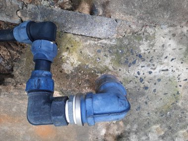 Eski sıkıştırma boru eklemleri. HDPE 90 derece siyah dirsek beton arka plandaki içme su borularını fotokopi alanına bağlıyor. Odaklan ve nesneleri seç.