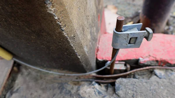 Toprak çubuğu kıskaçları. Elektrik sızıntısını önlemek için beton elektrik direklerinin yanına tel döşenmiş metal zemin çubuğu. Seçici odak