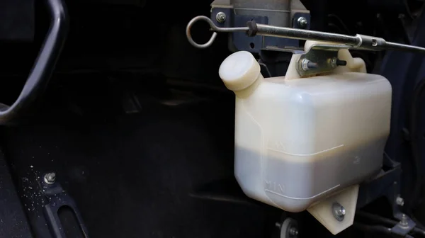 Beyaz fren sıvısı deposu. Fren hidroliği kasesi koyu renkli arka planda ve fotokopi alanı var. Otomobil parçaları konsepti. Odaklan ve bir nesne seç