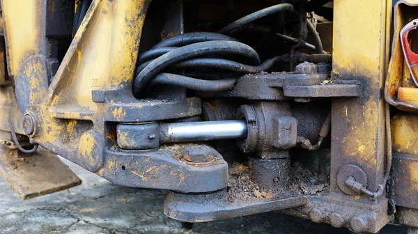 Cylinder and rod with old hydraulic hoses. Long-term use of heavy machinery causes the hydraulic system to deteriorate and dirty with old oil left on the equipment. Close focus and select an object