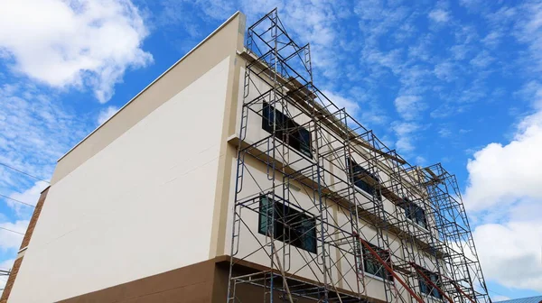 Scaffolding built next to the new building. On a blue sky background there are white clouds with a copy space. selective focus