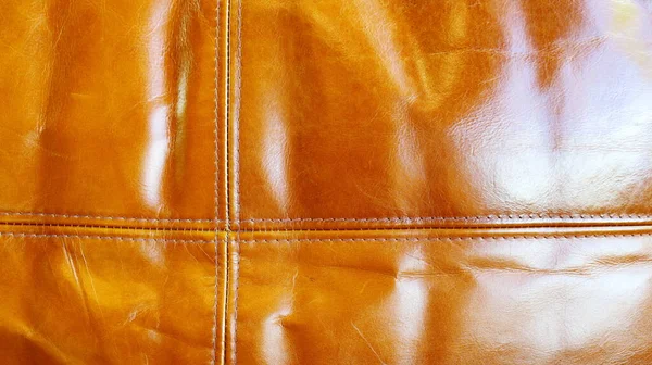Kahverengi deri koltuk dikişi. Arka plan olarak eski kahverengi deri yama işi. Seçici odak