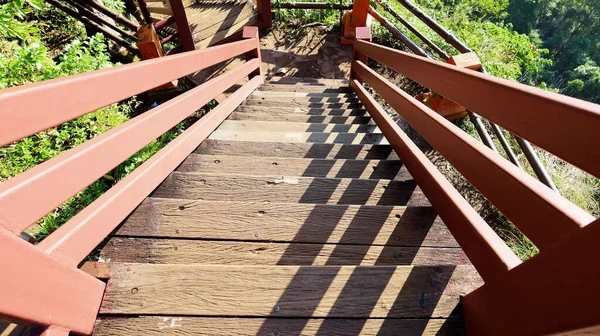 Shadow lines on the wooden bridge. Three dimensions of beautiful shadows on a wooden bridge on a sunny day and clear winter in Thailand. On a green tree background. Selective focus