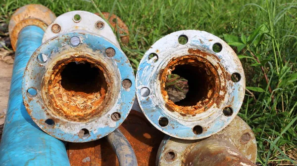 Old metal pipes clogged twin. Suspended solids in water contaminated with iron and manganese cause scale and rust to clog up inside water pipes on a lawn background with a copy area. selective focus