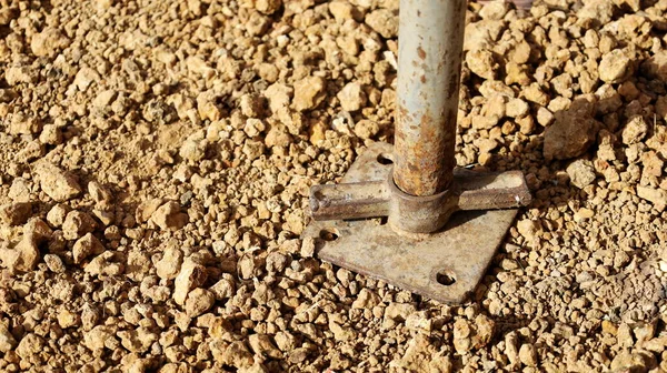 Jack base or old rusty screws. The jack base adjusts the height of the scaffold to support the construction site. On a light brown ground with a copy area. Selective focus