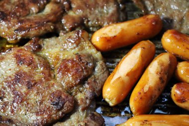 Sosisli sandviçi yakın ve tavada ızgara domuz bifteği. Tam kare. Yakın odaklan ve konuyu seç..