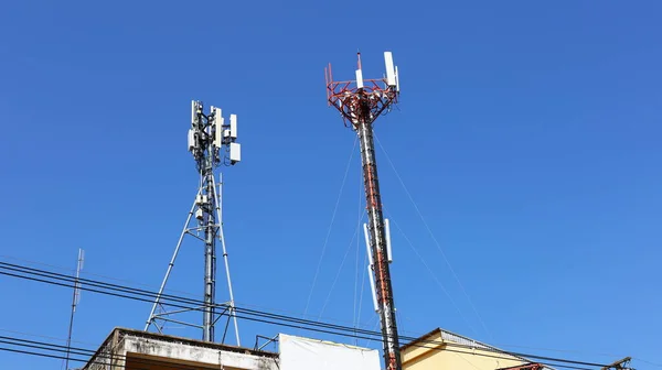 Double telecommunication towers. A 4 G or 5 G wireless telephone communication device is installed on the roof of the building. On a blue sky background with a copy space. Selective focus