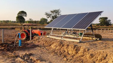 Güneş panelleri ve su pompaları. Panel, tarım çiftlikleri için su altı pompaları kullanılarak güneş enerjisi veya fotonları elektrik enerjisine dönüştürür. Traktörün arka planında ve gökyüzünde. Seçici odak