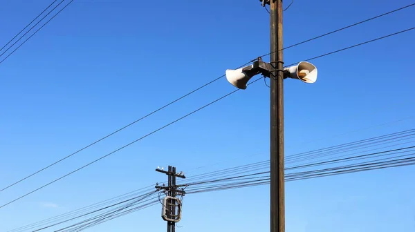 金属製の柱にホーンスピーカー ポールと明るい青空に電線の背景にコミュニティ内のニュースを通信するための放送技術 選択的焦点 — ストック写真