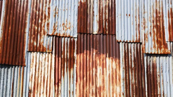 Rusty old galvanized wall. Metal background wavy red brown and silver grunge texture nasty. Full frame rate background for design. Selective focus