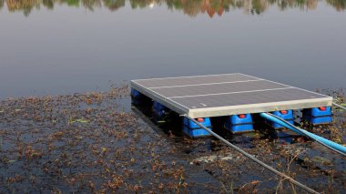 Suyun üstündeki güneş paneli. Kirli güneş paneli, su arka planında su pompalamak için elektrik üretmek için bir gölette su yüzdürür ve fotokopi alanı ile gölgelendirir. Seçici odak