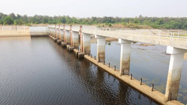 Weir Geçidi 'nin sağlam yapısı. Kurak mevsimde çevre tarımında yeşil ağaç arka planına karşı su kontrolü için açık alan Wier. Weir Ban Mai Surin, Tayland.