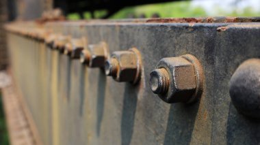 Eski köprü yapılarında fındık ve cıvatalar. Siyah çelik kirişlerin üzerinde demiryolu köprüsünün bir parçası olan birçok çapa cıvataları ve gölgeli güneş vardı. Odaklanma ve nesne seçimini kapat