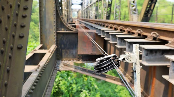 Sling cable for changing train tracks. A wire rope with a pulley for controlling the rail switch is mounted on the side of the rail on a steel bridge with copy area. Selective focus