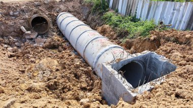 Ana deliği ve eski boruyu kapatın. Hendekte çürümüş eski boruları olan yeni beton kanalizasyon sistemi ve fotokopi alanı olan bir çit inşa etmek için. Seçici odak