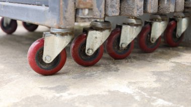 Several hinged door wheels. Dirty PU or Polyurethane plastic dial castors are lined up to enable convenient door movement over cement background with copy space. Close focus and choose content.