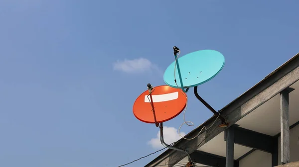 屋根の上のデュアル衛星料理 赤と青のデジタルテレビ受信機のプラーク斜めに配置した コピースペースのある青い空の背景に 選択的焦点 — ストック写真