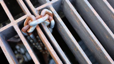 Paslı metal zincirler çelik bir ızgarada asılı. Cihazı şehir kanalizasyon sisteminin ana deliğine asmak için eski bir metal zincir. Odaklan ve içeriği seç