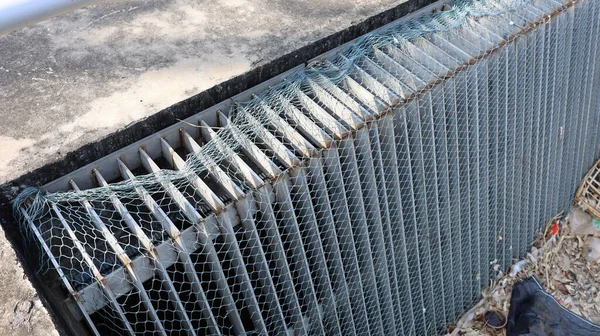 Mesh covering the metal screen to trap waste. Devices to prevent debris from clogging the city sewage canals, sanitation systems. Selective focus