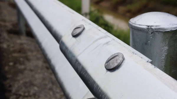 Steel nut on metal barrier. Screws and nuts connect roadside railings. selective focus