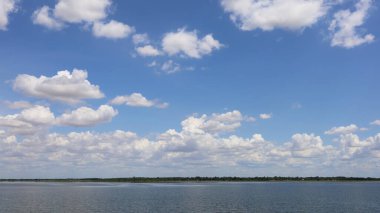 Açık bir günde gökyüzünde beyaz bulutlar. Yağmur mevsiminin bulutları, fotokopi alanı olan güzel bir rezervuarın üzerinde. Seçici odak