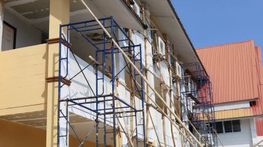 Binanın önünde metal iskeleler var. Binanın alt tarafını boyamak için bambu destekli yapı iskelesi. Seçili odak