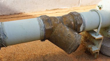 Pirinç rengi Y-Süzgeci yakın çekim. Beyaz borudaki eski Y-Süzgeci su tedarik sisteminde enkaz ya da çakıl yakalamak için bir araçtır. odak seç