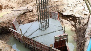 İskele tabanı ve çelik çerçeve. Evlerin ya da binaların beton kutupları su dolu bir toprak çukurunda fotokopi alanı var. Seçici odak
