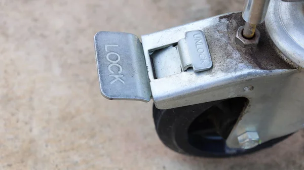 Caster 'lar ve metal kilitler. Eski kaydırma tekerleği tipinin arka plandaki üst metal plakayı kaydırarak kilitleme ve açma sistemi vardır. Yakın mesafeden odak seç