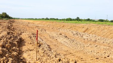 İnşaat alanında kırmızı tahta çubuk. Arka planda yeşil ağaçlar ve beyaz gökyüzü. Seçici odak