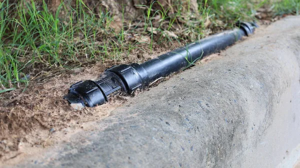 Straight Coupling of plumbing pipes. Black PB pipe couplings located above the ground on the side of the outdoor pavement. Select focus at close range