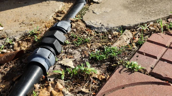 Tesisat borularından oluşan düz bir bağlantı. Yerin üstünde, kaldırımın kenarında siyah PB boru bağlantıları var. Yakın mesafeden odak seç