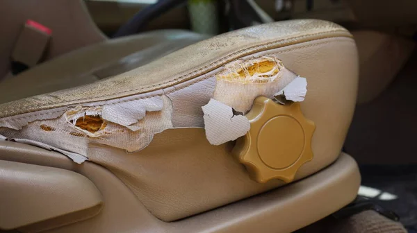 Eski araba koltuğu hasar görmüş. Kullanımdan yırtılmış sentetik deriden yapılmış krem renkli araba koltukları koyu bir arka plana sahiptir. Seçici odak