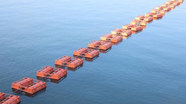 Suyun yüzeyindeki metal şamandıralar. Barajdaki turuncu şamandıraların yakın plan çekimleri mavi su arka planındaki tehlike bölgesini seçici bir odak noktasıyla işaretliyor.