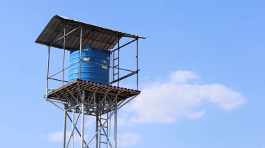 Su tankı kulede. Mavi gökyüzü arka planında, seçici odaklı mavi plastik su tankı..