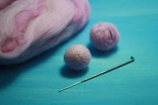 Balls of colored wool for making beads. Blue background.