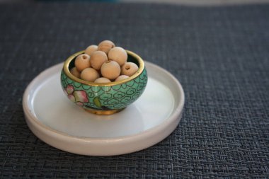 Gri arka planda cam bir tabakta tahta boncuklar..