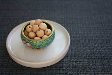 Gri arka planda cam bir tabakta tahta boncuklar..