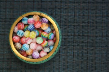 Cam bir fincan tabağında renkli boncuklar. Üst görünüm