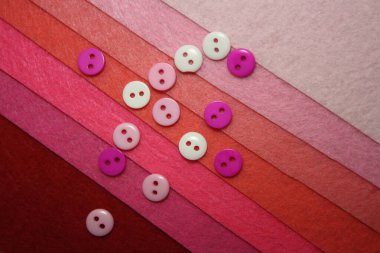 Pembe keçeli arka planda renkli düğmeler. Yapı