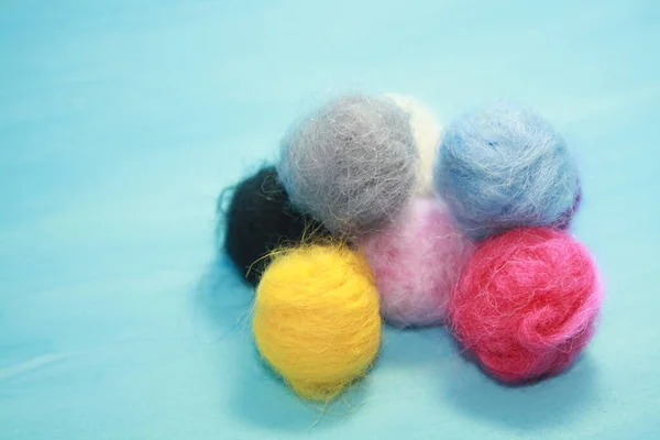 Balls of colored wool for making beads. Blue background.