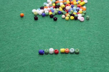 Yeşil arka plana yayılmış çok renkli boncuklar. Metin için boşluk.